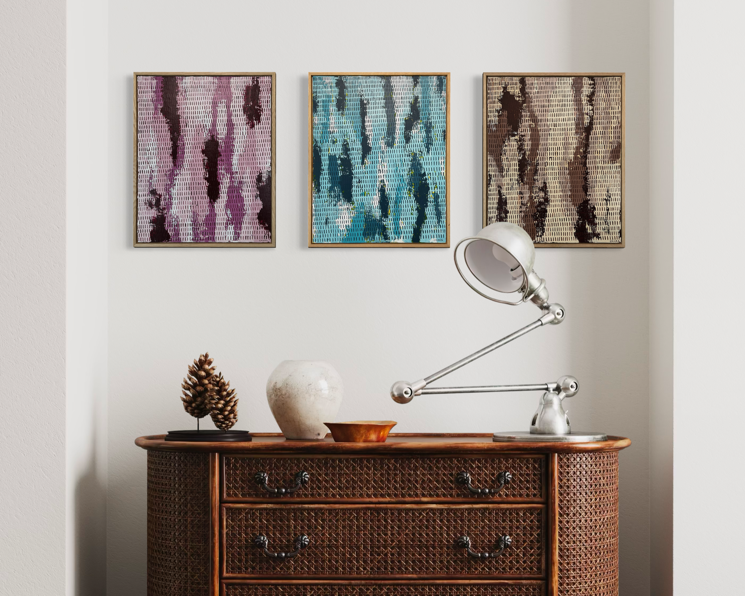 Wicker dresser with decorative items against a white wall with abstract art.